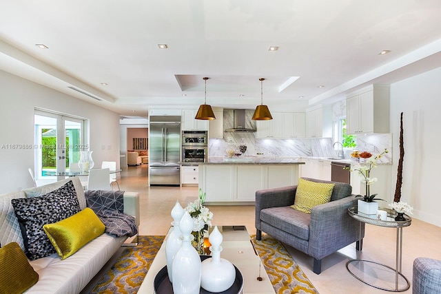 living room with light tile patterned floors, a raised ceiling, plenty of natural light, and sink