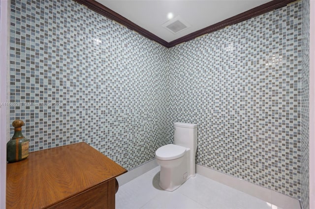 bathroom with tile patterned flooring, toilet, tile walls, and ornamental molding