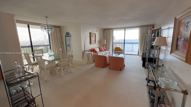 carpeted living room featuring an inviting chandelier, a water view, and floor to ceiling windows