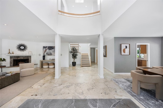 foyer entrance featuring a tiled fireplace and a towering ceiling