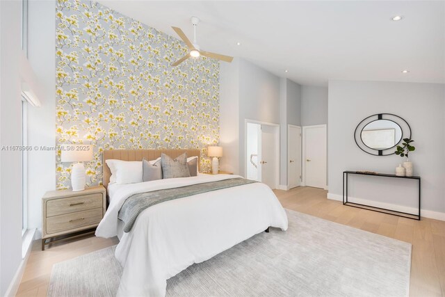 bedroom featuring ceiling fan, light wood-type flooring, and a high ceiling