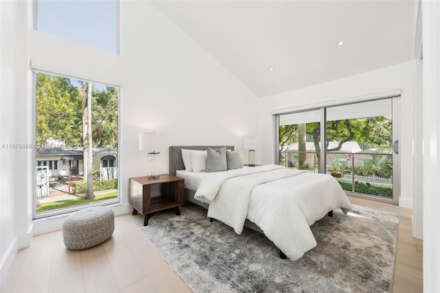 bedroom with high vaulted ceiling, access to outside, light wood-type flooring, and multiple windows