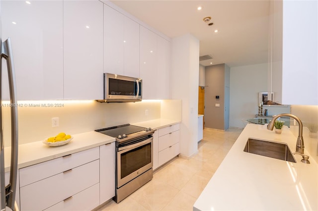 kitchen featuring white cabinets, stainless steel appliances, sink, and light tile patterned floors