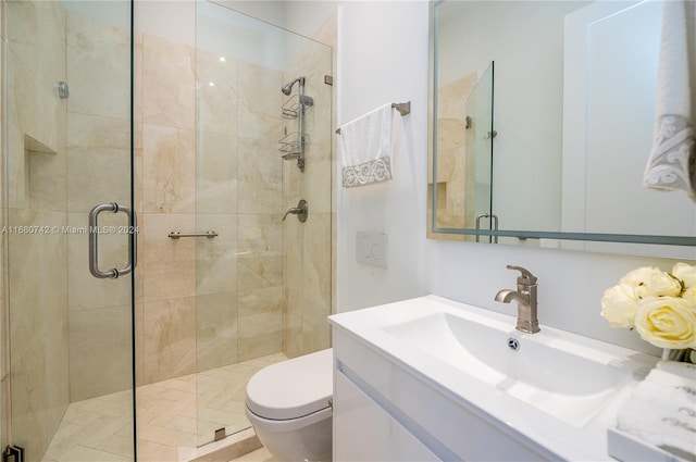 bathroom featuring a shower with door, toilet, and vanity