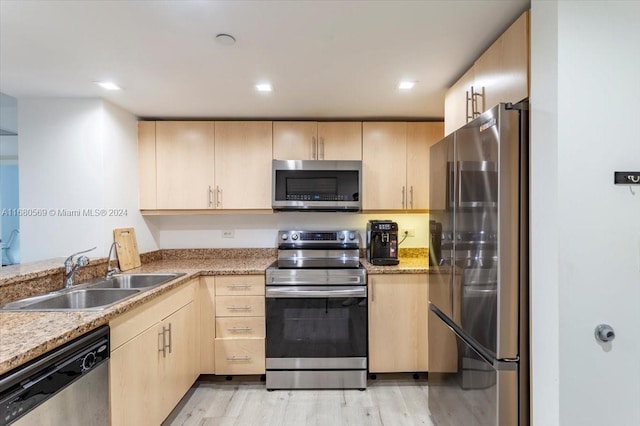 kitchen featuring light brown cabinets, light stone countertops, sink, light hardwood / wood-style floors, and stainless steel appliances