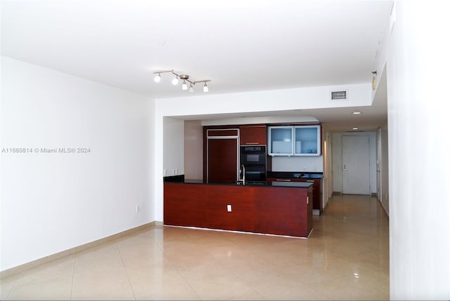 kitchen featuring kitchen peninsula, black double oven, light tile patterned flooring, and paneled refrigerator