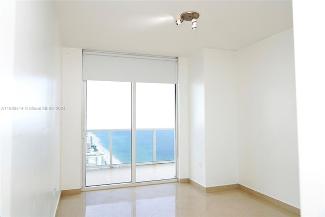 tiled spare room featuring a water view