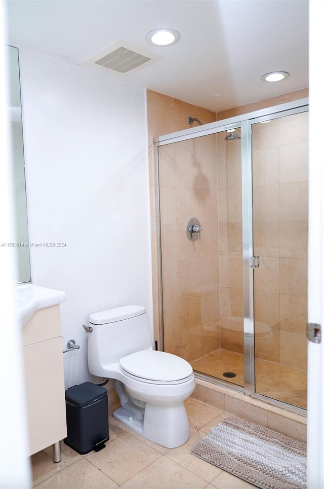 bathroom featuring vanity, a shower with shower door, toilet, and tile patterned flooring