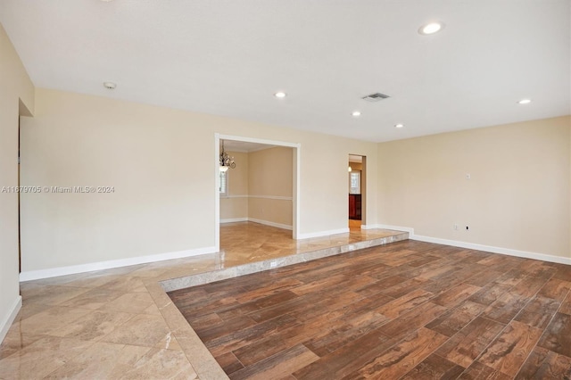 unfurnished room with light hardwood / wood-style flooring and an inviting chandelier