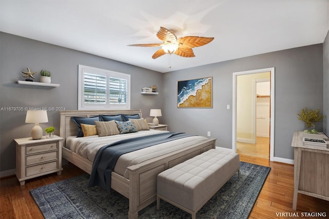 bedroom featuring ceiling fan, a walk in closet, and hardwood / wood-style floors