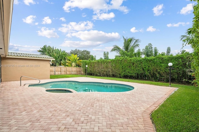 view of pool with an in ground hot tub, a patio area, and a lawn