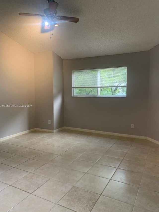 tiled empty room with a textured ceiling and ceiling fan