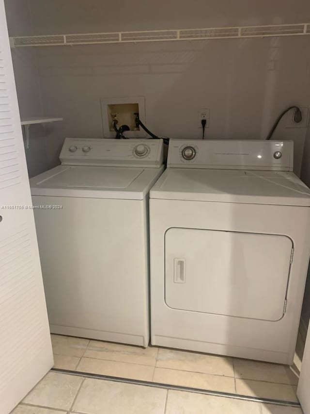 laundry area with independent washer and dryer and light tile patterned floors