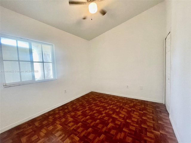 spare room featuring dark parquet floors, vaulted ceiling, and ceiling fan