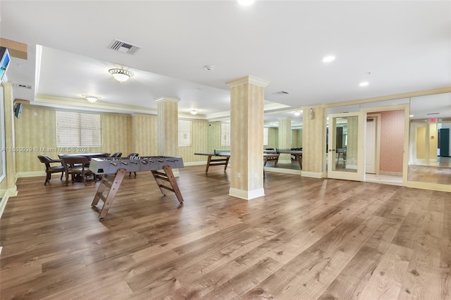 recreation room featuring crown molding, wood-type flooring, and decorative columns