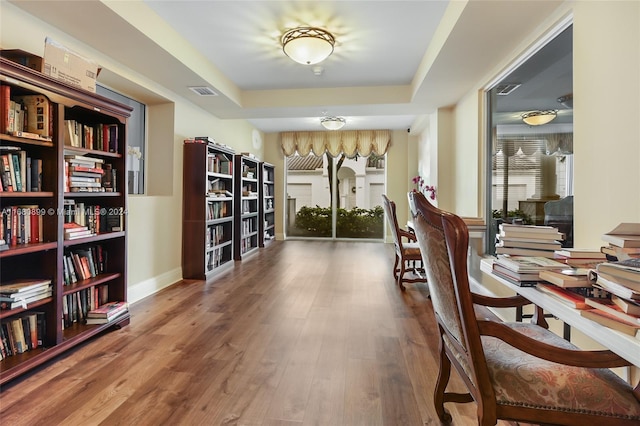 sitting room featuring a tray ceiling and wood-type flooring