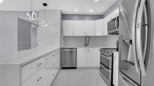 kitchen featuring appliances with stainless steel finishes, sink, kitchen peninsula, decorative light fixtures, and white cabinets