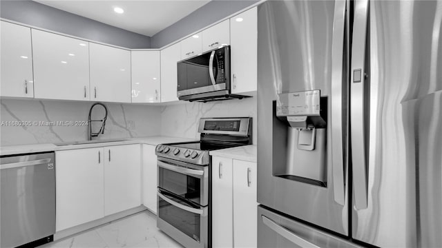 kitchen with tasteful backsplash, sink, white cabinetry, stainless steel appliances, and light stone counters