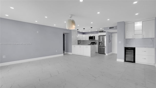 kitchen featuring beverage cooler, backsplash, appliances with stainless steel finishes, white cabinetry, and pendant lighting