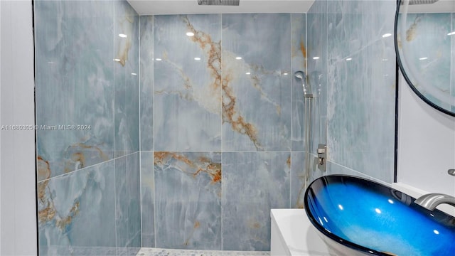 bathroom featuring sink, a shower, and tile walls