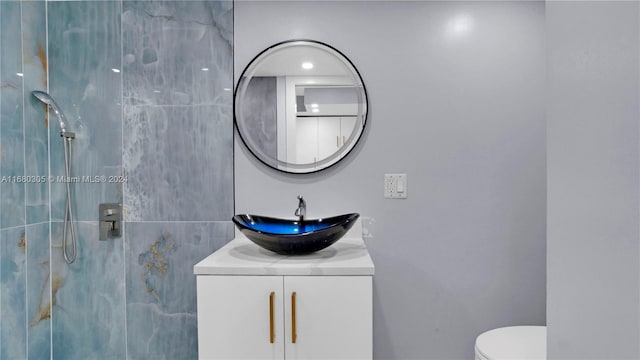 bathroom featuring vanity, toilet, and a tile shower