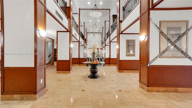 corridor featuring light parquet flooring, ornamental molding, a high ceiling, and wooden walls