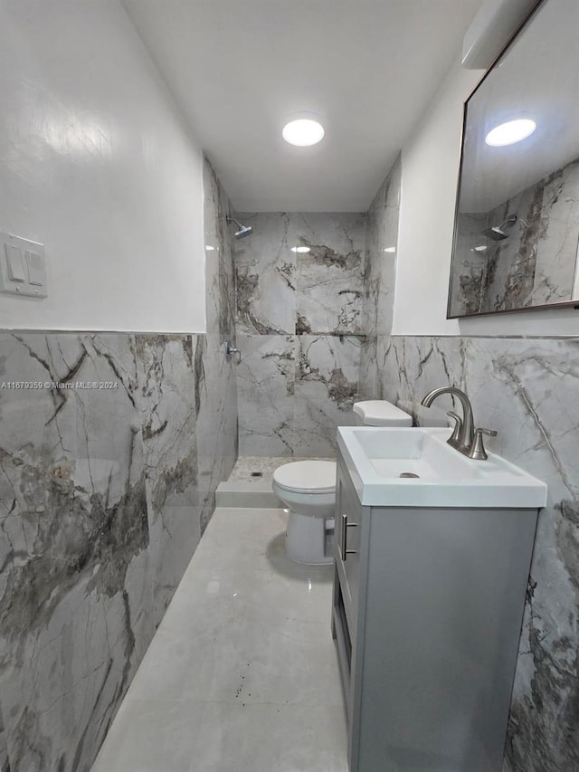 bathroom featuring tile walls, vanity, toilet, and tiled shower