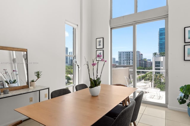 dining space featuring a healthy amount of sunlight, a towering ceiling, and light tile patterned floors