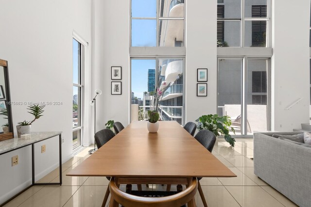 dining area featuring a towering ceiling and light tile patterned flooring