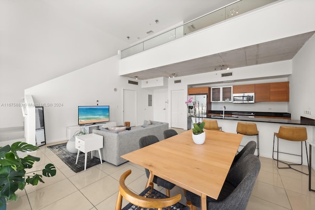 dining area with sink, a towering ceiling, and light tile patterned floors