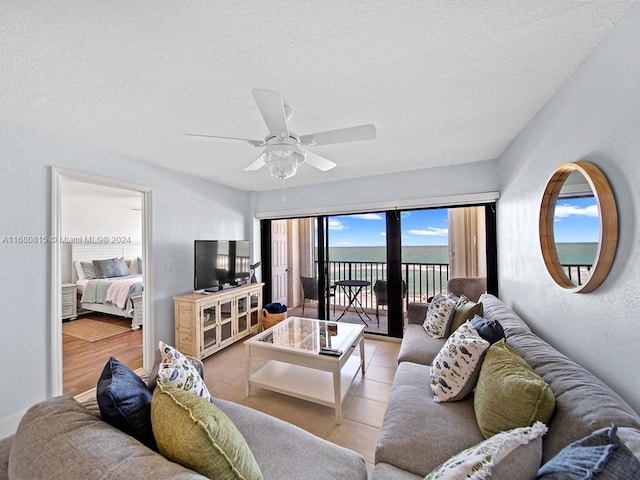 tiled living room featuring ceiling fan and a textured ceiling