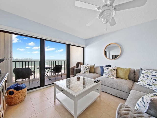 tiled living room with a textured ceiling, a water view, and ceiling fan