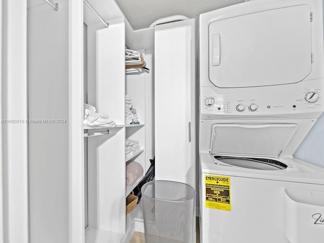 laundry room with a textured ceiling and stacked washing maching and dryer