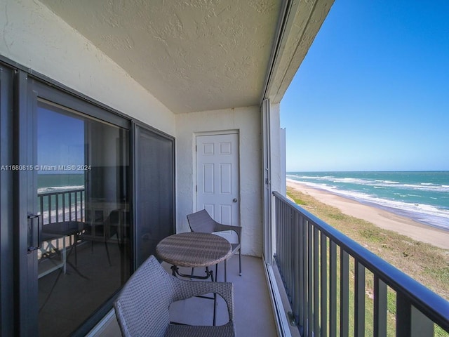 balcony with a water view and a view of the beach