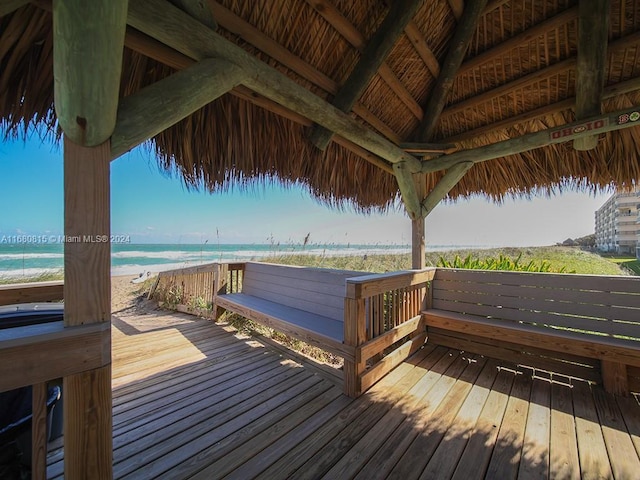 wooden terrace featuring a view of the beach, a gazebo, and a water view