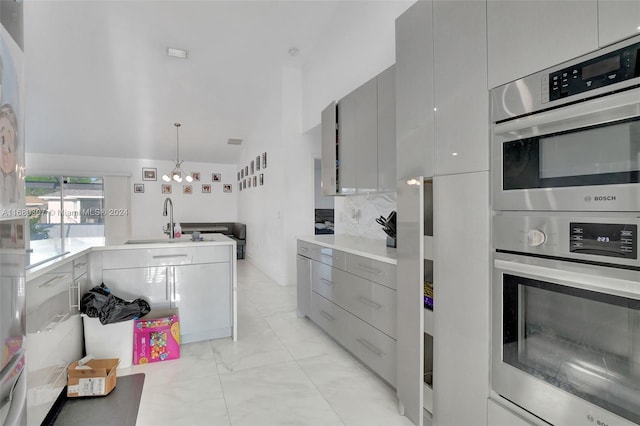 kitchen with decorative backsplash, stainless steel double oven, decorative light fixtures, and gray cabinetry