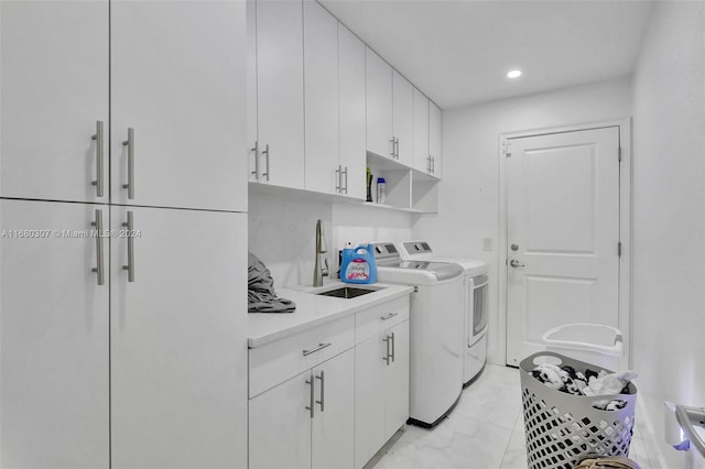 clothes washing area with sink, independent washer and dryer, and cabinets