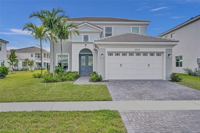 view of front of property with french doors, a front yard, and a garage