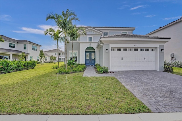 view of front of home with a front lawn, a garage, and french doors