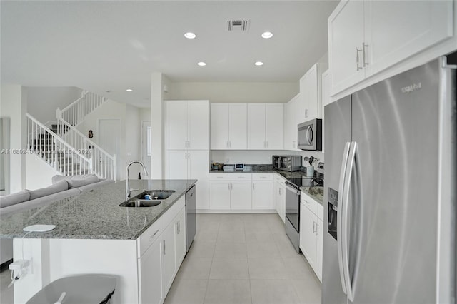 kitchen featuring appliances with stainless steel finishes, an island with sink, white cabinetry, and sink