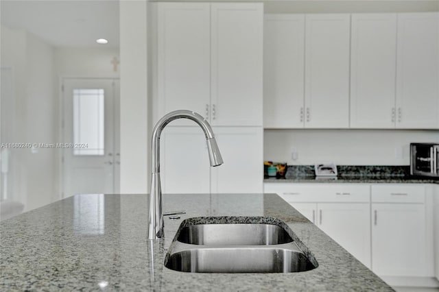 kitchen with white cabinetry, sink, and dark stone counters