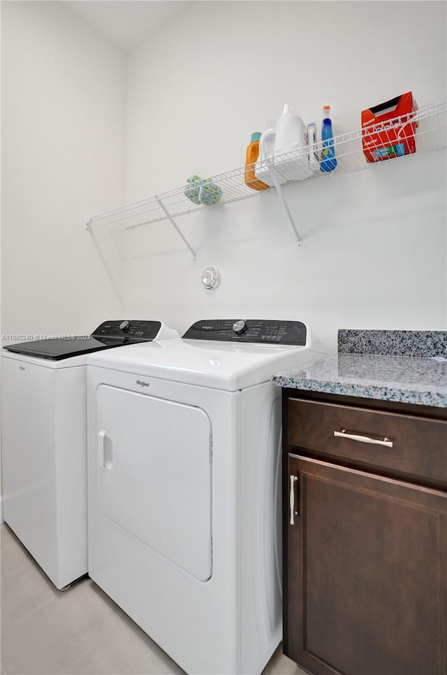 clothes washing area with washer and clothes dryer and cabinets