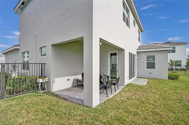 rear view of property featuring a lawn and a patio