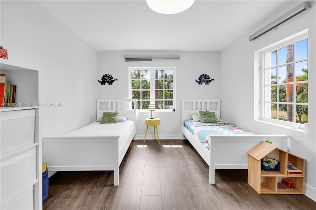 bedroom with multiple windows and dark hardwood / wood-style flooring