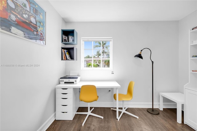 home office with built in desk and dark hardwood / wood-style flooring