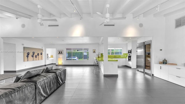 living room featuring beam ceiling, sink, a high ceiling, and ceiling fan