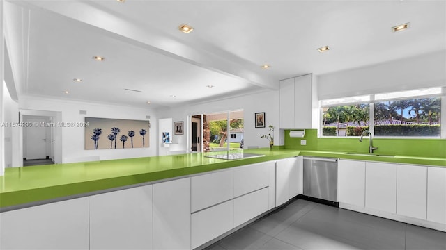 kitchen featuring kitchen peninsula, white cabinets, stainless steel dishwasher, dark tile patterned floors, and sink