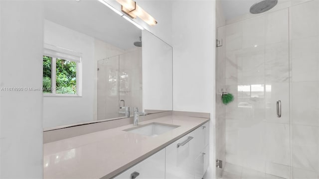 bathroom featuring a shower with door and vanity