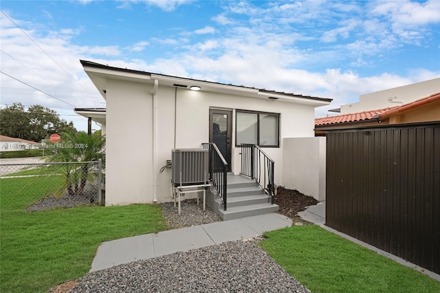 rear view of property featuring a yard and cooling unit