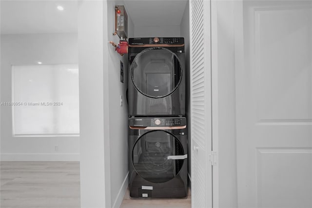 laundry room featuring stacked washer and dryer and light hardwood / wood-style flooring